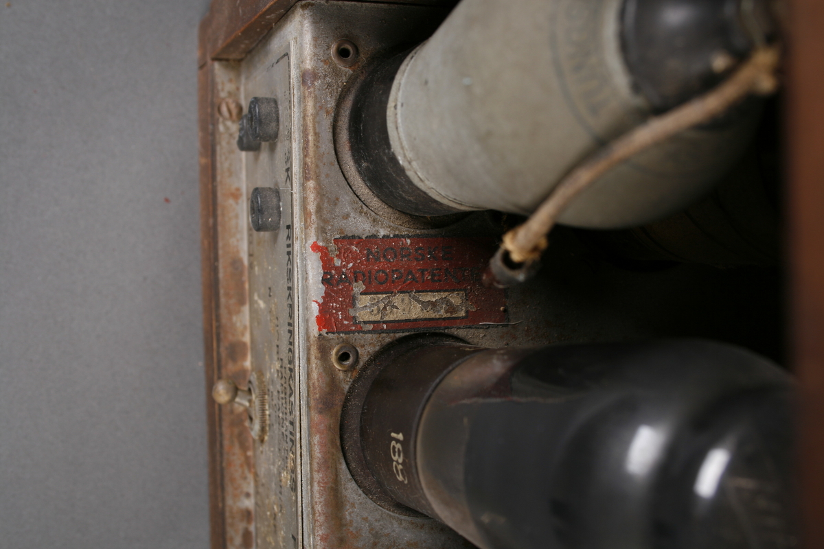 Radio i enkel kasse av finer. Rund høyttaler på venstre side av front. Skala med ramme i bakelitt på høyre side, under dette tre knapper i bakelitt: Volum, innstilling frekvens og av-på. Høyttaleren er omrammet av en ring i bakelitt og trukket med stoff.

Innvendig er apparatet delt i to, tilgang fra baksiden. På høyre side er høyttaleren og på venstre side radiorør og elektronikk med utgang for ledninger.