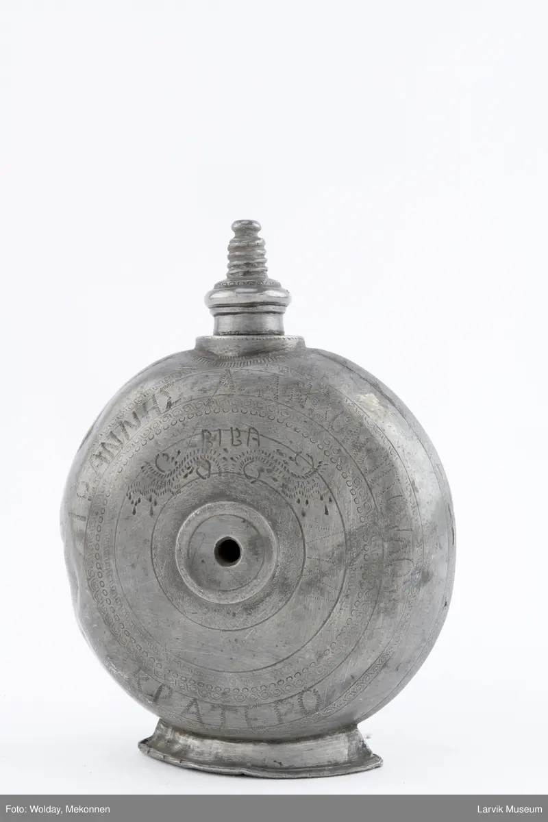 Påført bokstaver (greske?) og dekor og årstall 1930  på den ene siden og bokstaver (greske?), dektor og bokstavene BIBA på den andre siden