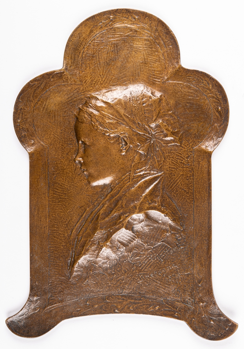 Relief i brons med profilporträtt av ung kvinna från Bretagne. Gjuten hos Herman Bergmans Bronsgjuteri i Stockholm.
