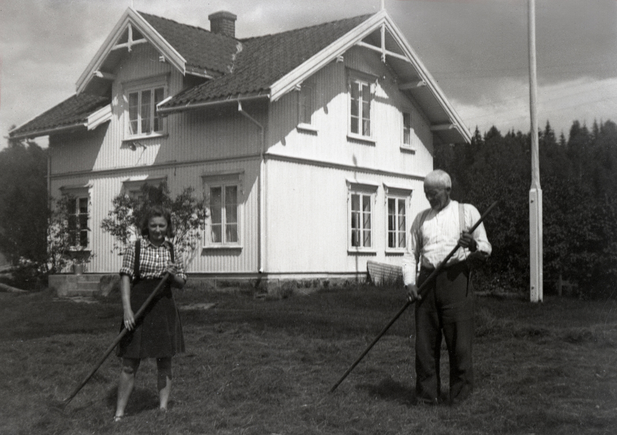 Eldre mann og yngre kvinner med ljåar utanfor eit hus.