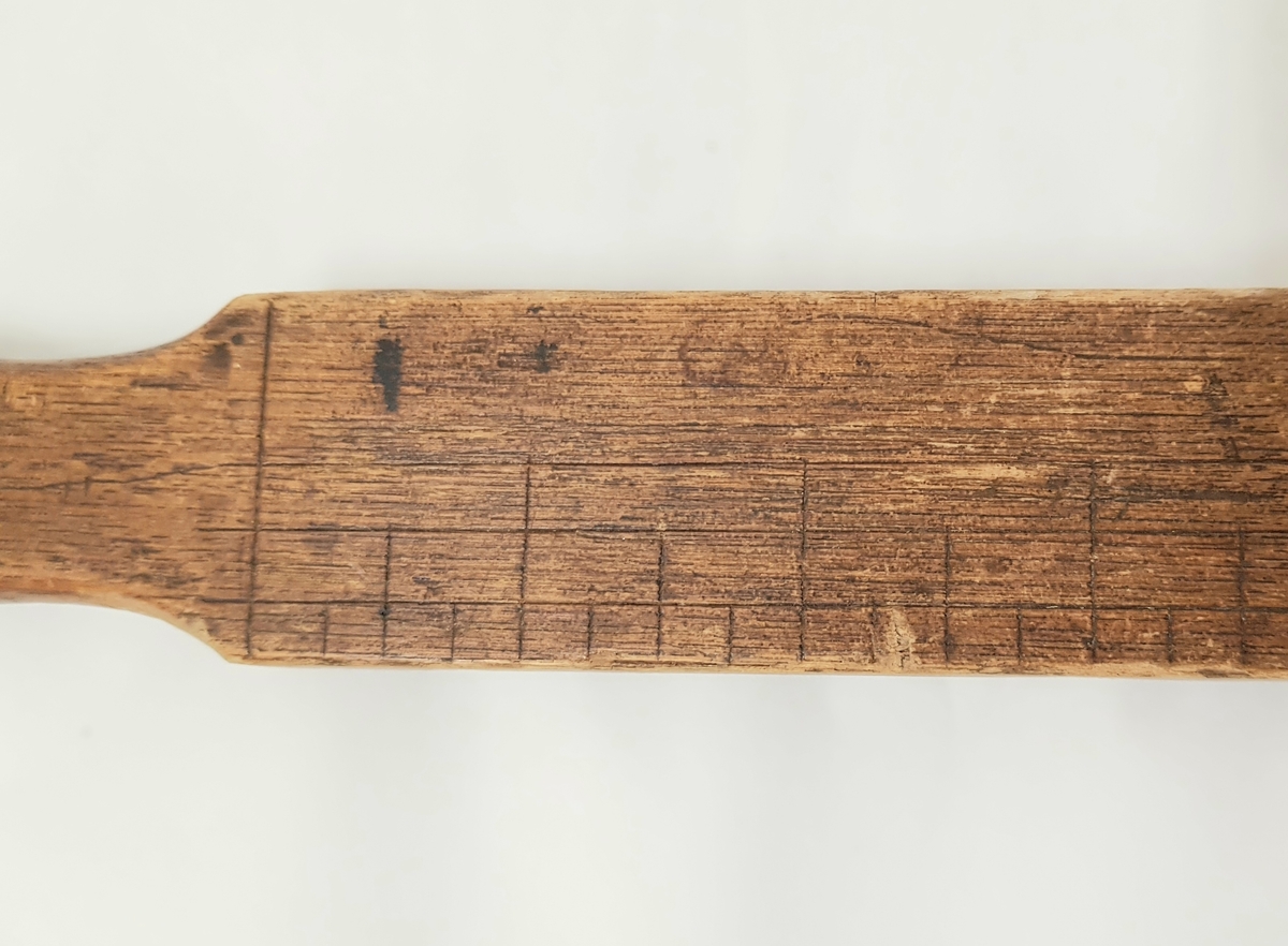Et smalt stykke tre med gjentakende markeringer innrisset i stykket