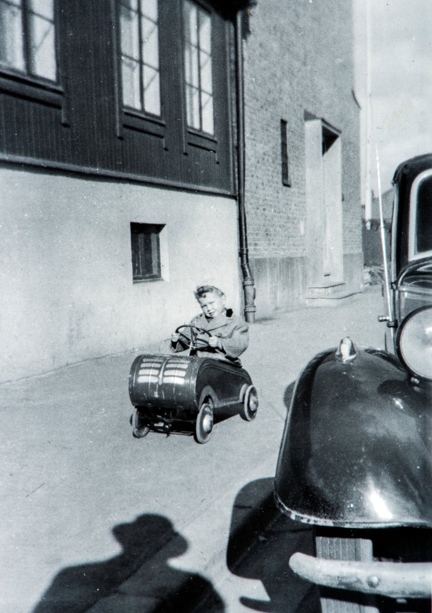 Barn og tråkkebil. Ved Torggata 113, sett mot øst rundt 1952. 
Arne Hesselberg i god fart på fortauet foran daværende Prestegård og med St. Torfinn kirke. Pastor Parthe bodde innenfor vinduene ovenfor.

 Familien Hesselberg leide en liten leilighet i venstre del av det brun(-gule) trehuset med kjøkken og soverom, samt stue vendt mot skoleplassen (Vestre torg) nedenfor. Vaskekjeller og vedbod under. Utedo bakerst i bakgården, bak sandkassen. Bilen til høyre, er Charles Hesselbergs gamle DKW - sort med gule sider - Oslo-registrert med A-17801