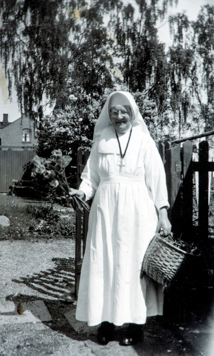Ukjent nonne, Tatt inne i haven til Torggata 113 mot nord rundt 1953. I bakgrunnen Hamar fengsel. Søster mmm