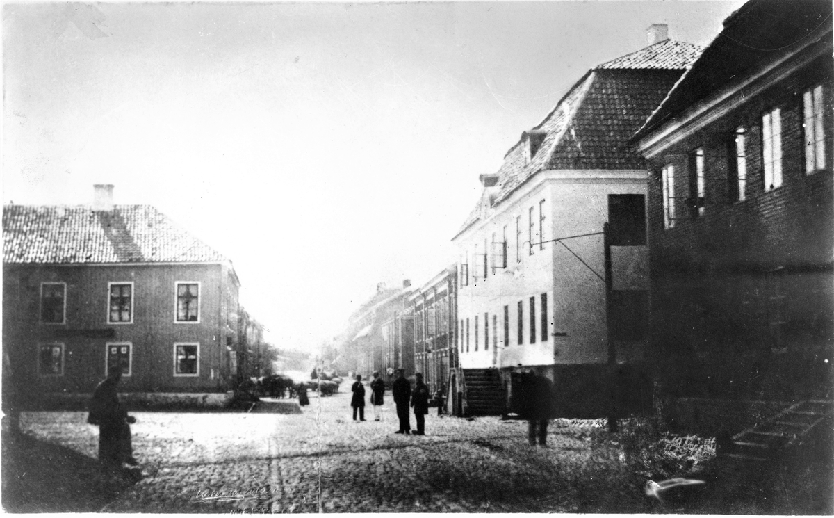 Kungsgatan före stadsbranden 1863, bilden tagen mot söder. Närmast i bild till höger ligger det s k Lundquistska huset från 1700-talet. Det vita huset till höger är det då ca hundraåriga Bruniuska huset, uppfört på 1760-talet. Släkten Brunius stammade från en dansk köpman Brune, varifrån en släktgren kom till Varberg på Karl XII:s tid. Till Bruniuska huset hörde ett lusthus med omgivande plantering. Efter branden lades ett tak på gårdens återstående grundmurar. Byggnaden kom sedan att kallas "Augusts källare". Där uppfördes Varbergs stadshus 1902 som idag inrymmer Stadshotellet.

Trähuset på vänstra sidan kallades Liedbergska huset eftersom tomten sedan 1700-talets senare del ägdes av den i staden framstående kommersrådet och riddaren Petter Gerhard Liedberg. Han var så förmögen att när konung Gustav IV Adolf 1794 på sin eriksgata genom Halland och togs emot hemma hos familjen Liedberg gick kungen med på att äta på Liedbergs silverservis då den var av så hög kvalitet och hade ett högst betydande värde. I vanliga fall användes alltid kungens egen silverservis.