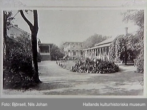 Restaurang Pehrssonska trädgården. Det var Börje Pehrsson som 1865 köpte lasarettsläkare Jakob Strömquists då tämligen nybyggda villa och öppnade där ett sommarvärdshus, då benämnt "Börje Pehrssons". Detta blev mycket populärt både bland stadens folk och tillresta kurortsgäster. Bilden är tagen från nuvarande Södra Hamnvägen, huset i fonden är en paviljong kallad "Baden-Baden". Strax framför skymtar musikpaviljongen med spira på taket uppförd 1879. Huset t v  är restaurangbyggnaden längs med Västra Vallgatan, med veranda åt väster. Huset t h är danspaviljongen byggd 1882. Bildens beteckning är "Personska trädgården".