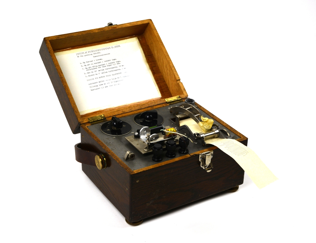 Provapparat kvicksilverströmbrytare. Provutrustning i metall monterad i brun trälåda. Innehåller instruktioner i insidan av locket samt medföljande lös manual med skötselinstruktioner.