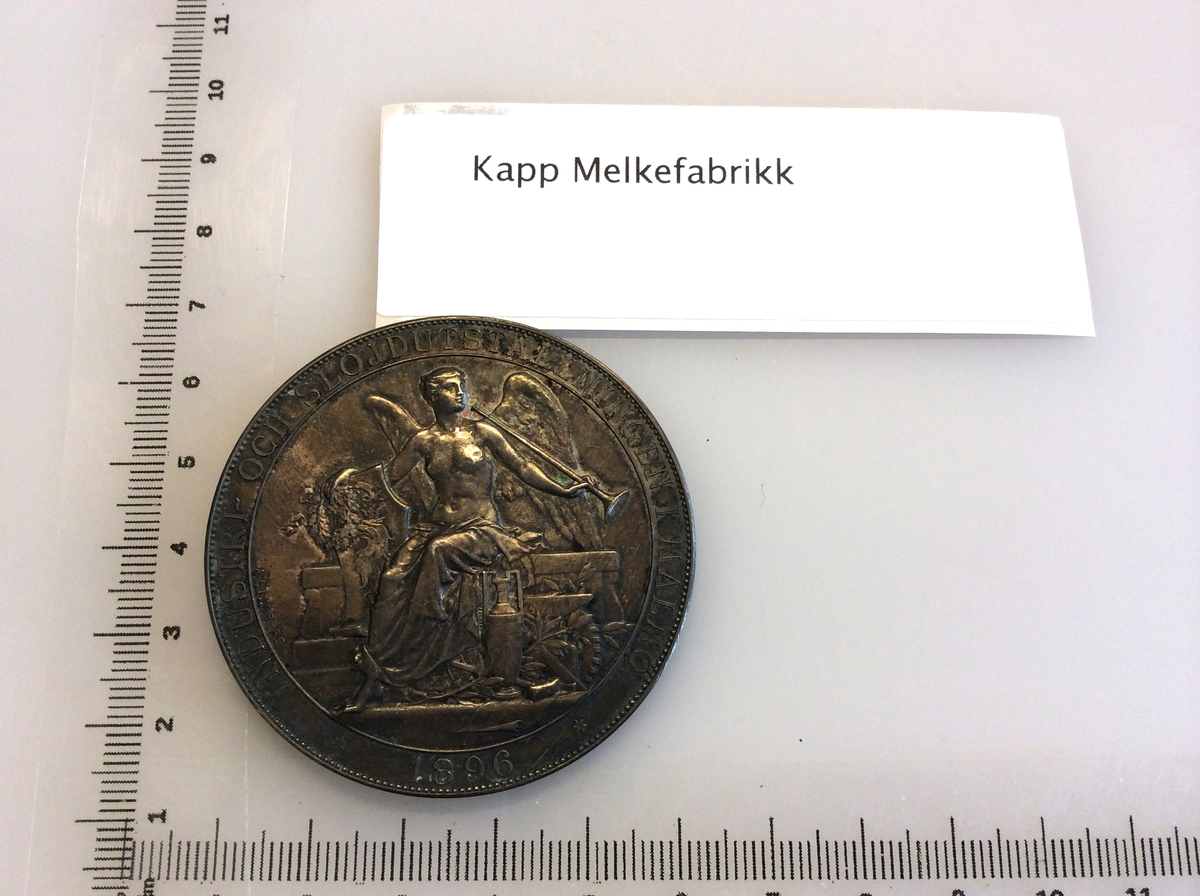 Etui med gråfarget mynt avbildet med Oscar II Norges konge på en side og en karakter fra gresk eller romersk mytologi på andre siden.