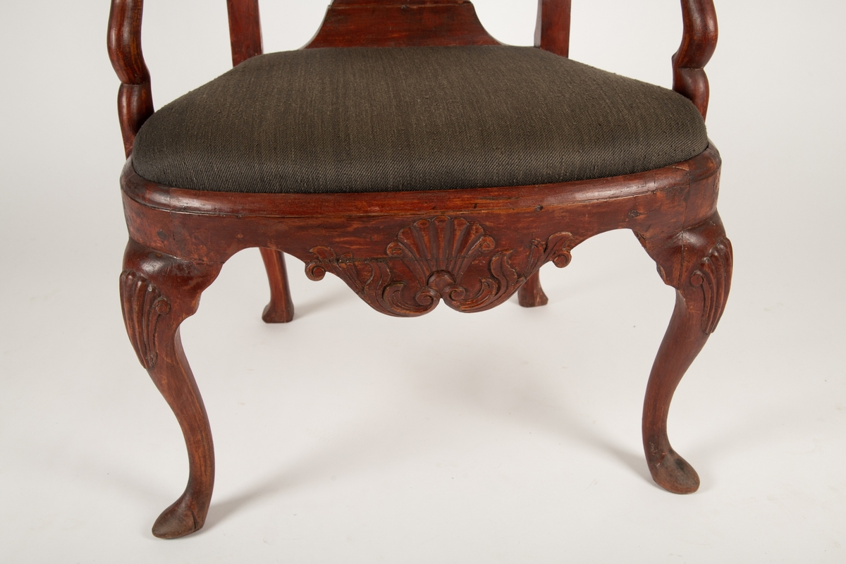 Høy, åpen, svungen rygg med balusterformet midtbrett,  toppstykke utskåret med skjell og blad. Løst sete  nedfelt i sargen, stoppet med sjøgress, trukket med blomstret trekk (ca. 1910). Svungne armlener.  Tunget sarg med skjell og blad utskåret i fronten,  svungne ben med skjell-løv på kneet, spiss fot.  Ingen bindeledd mellom benene.