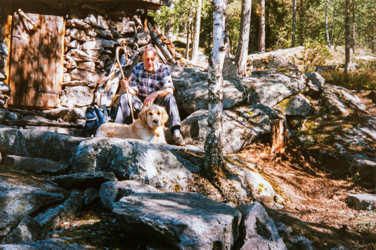 Arne Frydenlund og hunden Trym på tur i Vallset, Her ved steinbua som Oddmund Rønningsbakken har bygd opp. Ca 1995.