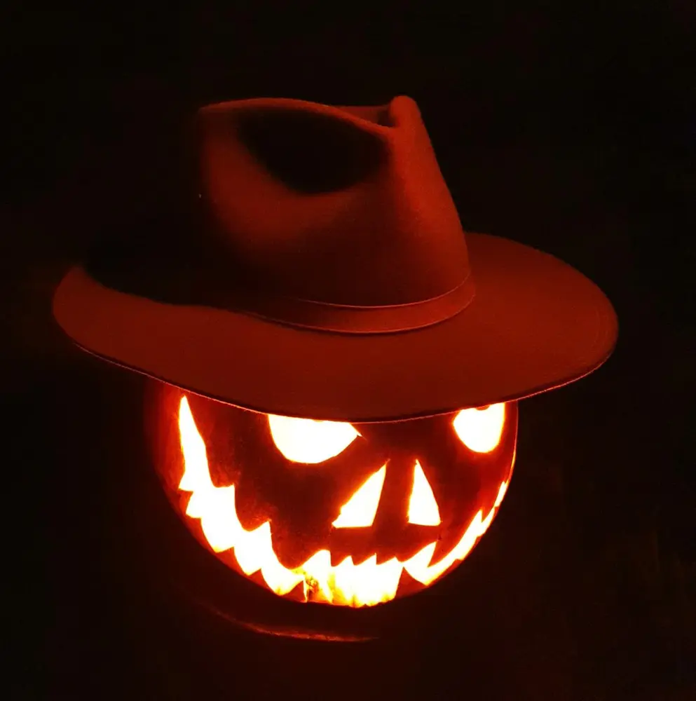 Lysende gresskar med cowboyhatt i mørket