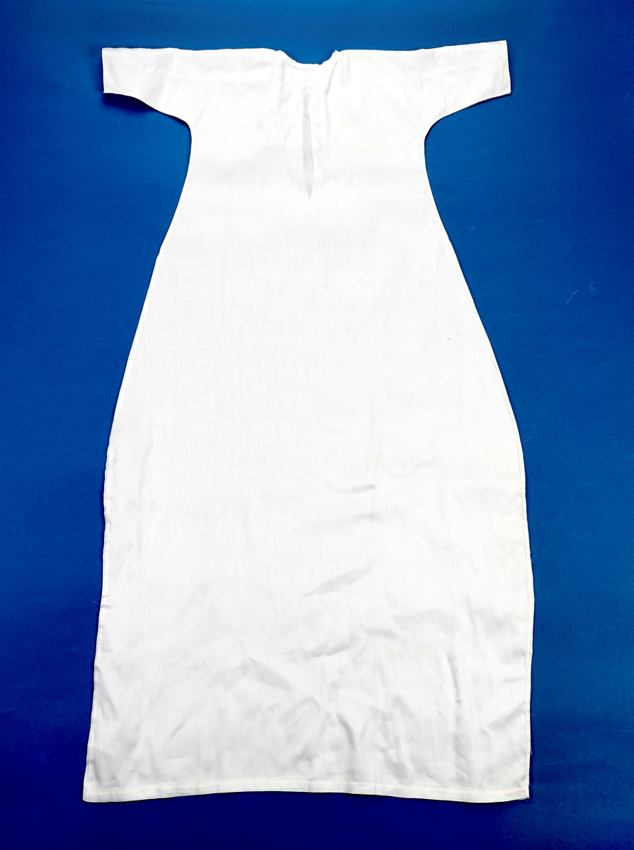 Dåpskjole med underkjole og belte.
Kjolen har rund hals med løpegang og knytesnor. Hele kjolen er klippet i ett stykke. skjøtt stoff på det ene ermet. Blondepynt i alle åpninger.  
Underkjolen er klippet i ett stykke. Rynket i halsen. Splitt bak med knepping øverst.
Bredt bånd der alle dåpsbarnas navn er brodert med henholdsvis blå og rosa skrift.