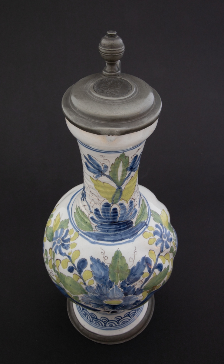 Polykrom blomsteroppsats på korpus og blomsterdekor på halsen. Asiatisk inspirert bølgemønster på foten. Myntavtrykk på lokket med portrett av Karl VII i profil og innskriften Carolus VII D. G. ROM. IMP. EMP. AVG. Dette er en forkortelse for Carolus VII. Dei Gratia Romanorum Imperator Semper Augustus.
