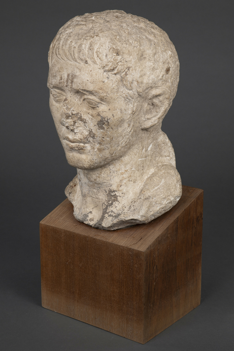 Byste i kalksten på fot av tre.