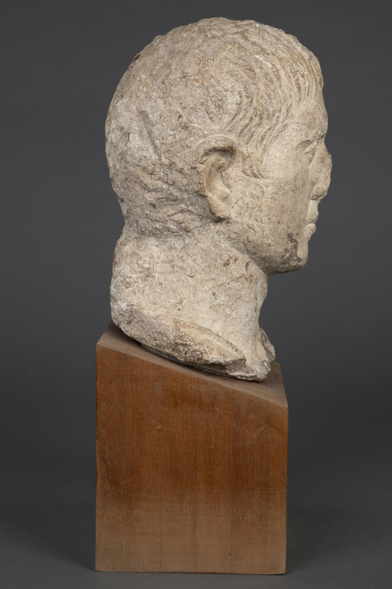 Byste i kalksten på fot av tre.