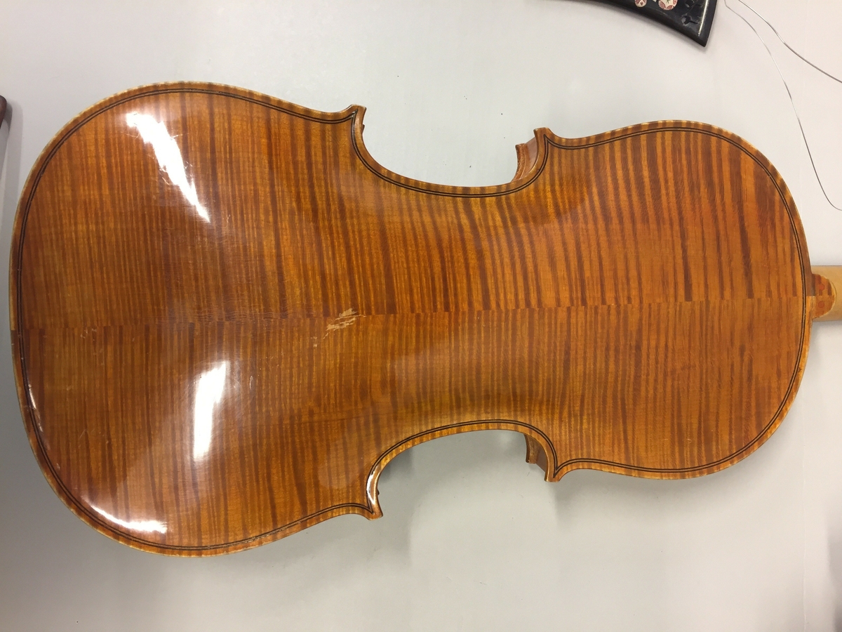 Fiolin med ein rosa blomst til dekor på bakre bru. Inni fela er det lapp med" Guldmedalje i Prorsgrund 1946 Aasmund. Ø .Hovden Telemark reparert 1935". Fiolinen ligg i eit brunt treskrin. Ein liten nøkkel er knytt fast til skrinet.