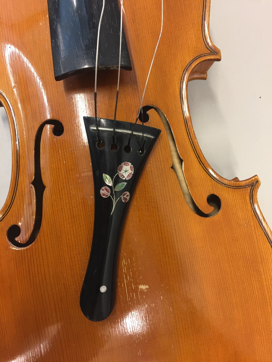 Fiolin med ein rosa blomst til dekor på bakre bru. Inni fela er det lapp med" Guldmedalje i Prorsgrund 1946 Aasmund. Ø .Hovden Telemark reparert 1935". Fiolinen ligg i eit brunt treskrin. Ein liten nøkkel er knytt fast til skrinet.