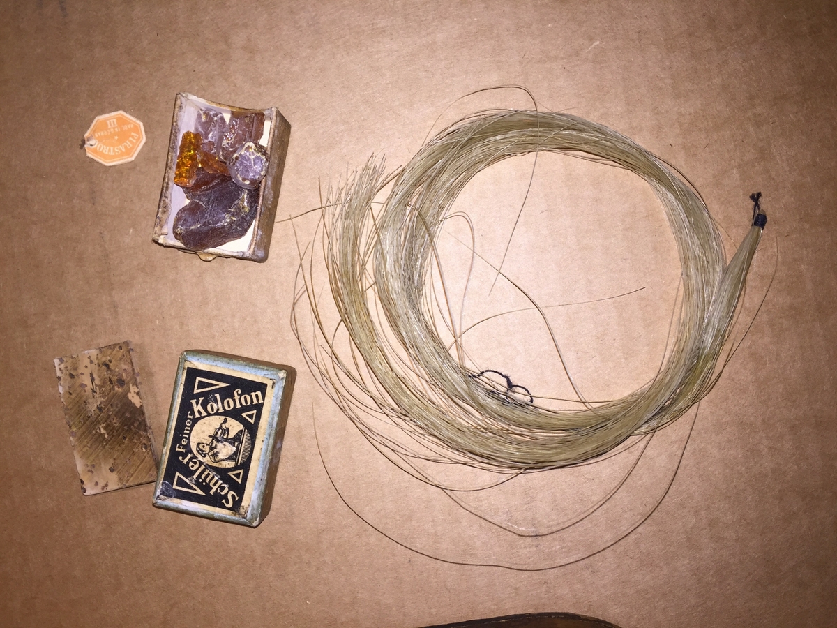 Fiolin med ein rosa blomst til dekor på bakre bru. Inni fela er det lapp med" Guldmedalje i Prorsgrund 1946 Aasmund. Ø .Hovden Telemark reparert 1935". Fiolinen ligg i eit brunt treskrin. Ein liten nøkkel er knytt fast til skrinet.