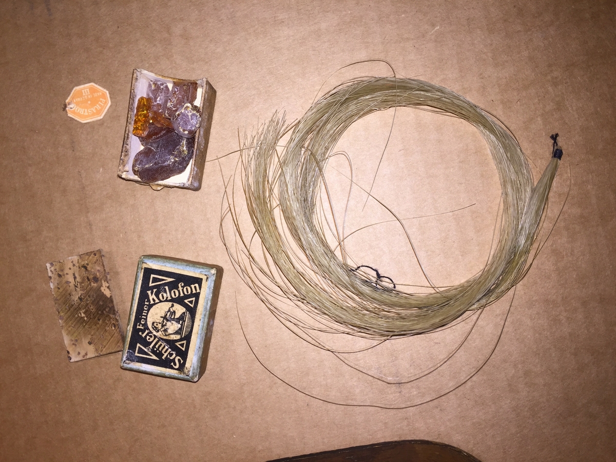 Fiolin med ein rosa blomst til dekor på bakre bru. Inni fela er det lapp med" Guldmedalje i Prorsgrund 1946 Aasmund. Ø .Hovden Telemark reparert 1935". Fiolinen ligg i eit brunt treskrin. Ein liten nøkkel er knytt fast til skrinet.