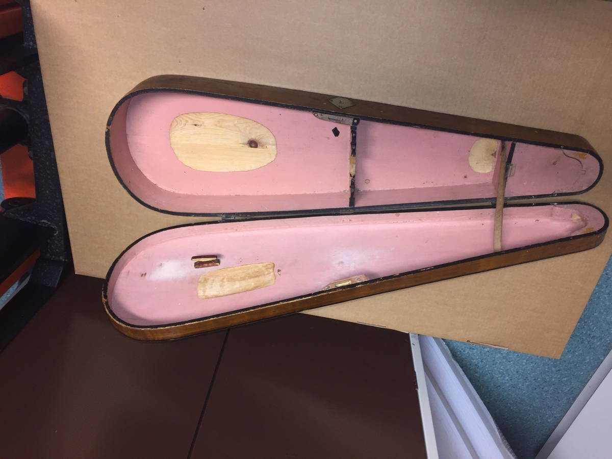 Fiolin med ein rosa blomst til dekor på bakre bru. Inni fela er det lapp med" Guldmedalje i Prorsgrund 1946 Aasmund. Ø .Hovden Telemark reparert 1935". Fiolinen ligg i eit brunt treskrin. Ein liten nøkkel er knytt fast til skrinet.