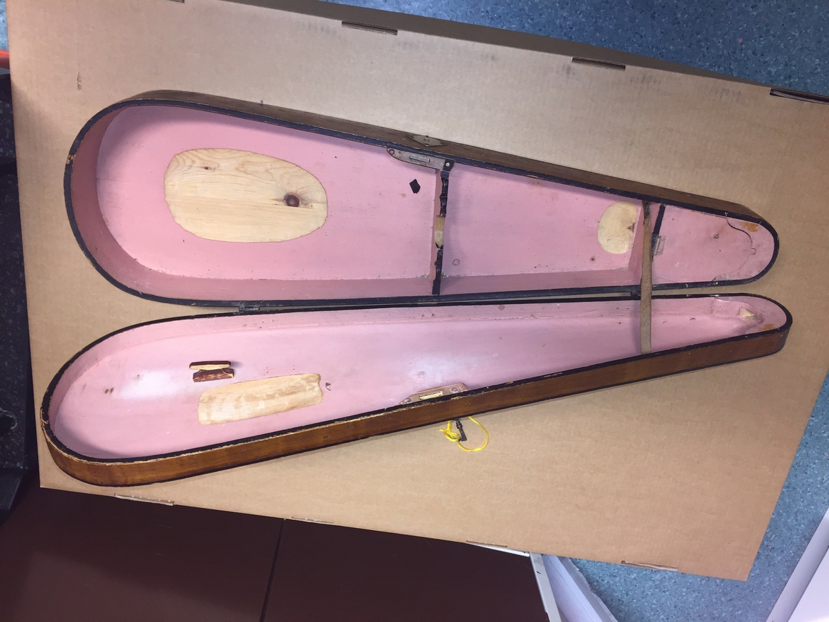 Fiolin med ein rosa blomst til dekor på bakre bru. Inni fela er det lapp med" Guldmedalje i Prorsgrund 1946 Aasmund. Ø .Hovden Telemark reparert 1935". Fiolinen ligg i eit brunt treskrin. Ein liten nøkkel er knytt fast til skrinet.