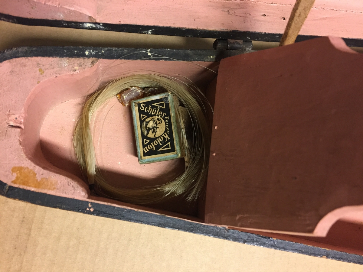 Fiolin med ein rosa blomst til dekor på bakre bru. Inni fela er det lapp med" Guldmedalje i Prorsgrund 1946 Aasmund. Ø .Hovden Telemark reparert 1935". Fiolinen ligg i eit brunt treskrin. Ein liten nøkkel er knytt fast til skrinet.