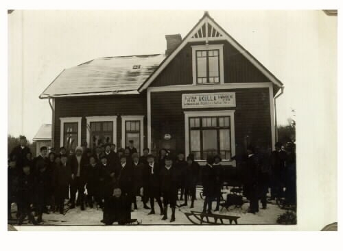 Vykort med stationshuset vid järnvägshållplatsen i Åkulla utmed Varberg-Ätrans järnväg, invigd 1911. Det är taget vintertid och en mängd resenärer är samlade på hållplatsen och i förgrunden syns en kälke. Byggnaden har nationalromantiska drag i sin arkitektur.