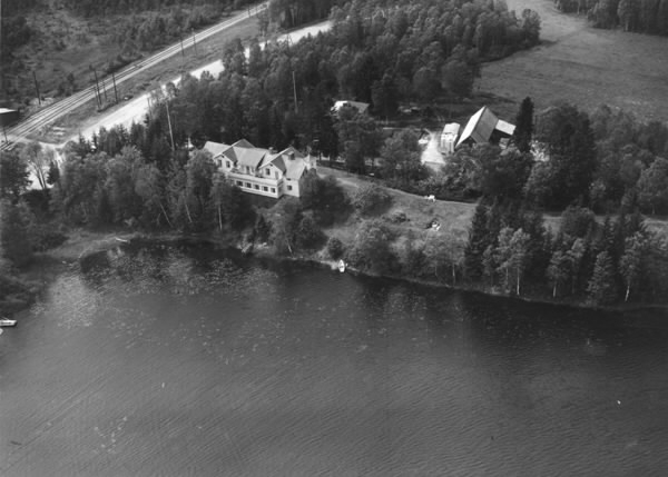 Flygbild över Semesterhemmet Solvik i Fegen vid sjön med samma namn. Vyn visar även järnvägen till vänster i bild. När Varberg-Ätrans järnväg invigdes 1911 kunde man från Ätran ta sig vidare till Fegen och Kinnared på tidigare anlagda järnvägar.
