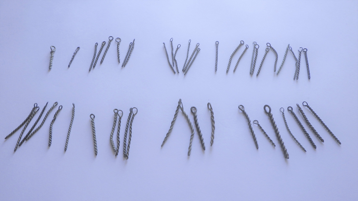 MALV: SE BESK., ST. L. 45 MM, MINSTE L. 16 MM, ST. DIAM. 2 MM, MINSTEDIAM. 1 MM. LAGET AV METALLTRÅD. GJENSTANDEN DANNET VED AT TYNNMETALLTRÅD (DIAM. 0, 5-1, 1 MM) ER LAGT DOBBEL OG SNODD I SPIRAL. ØYE IENDEN. NB! 2 HAR FLATTRYKT PARTI VED HULLET. 