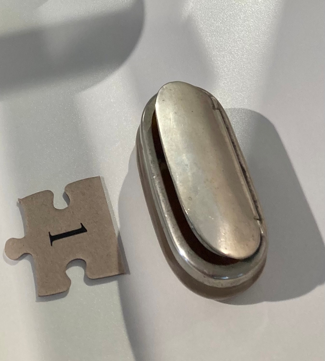 Oval snusdåse av horn, med lokk i metall. (Midt på bildet.)