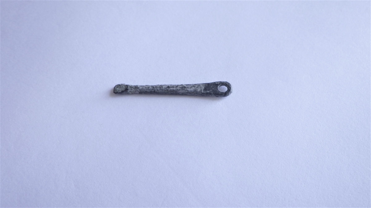 MALV: L. 31  ST. B. 4, 5 MM, BÅNDFORMET, FORMET SOM EN EN TORN, MEN FLAT. AVRUNDETE ENDER - SOM IKKE ER LIKE BUEDE. RESTER AV EN STIFT SITTERIGJEN I DEN SMALESTE ENDEN. 