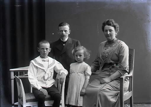 Ateljébild. Familjebild, föräldrar med en liten flicka och en pojke i 3/4 figur. Beställare: Stationsskrivare Helmer.
