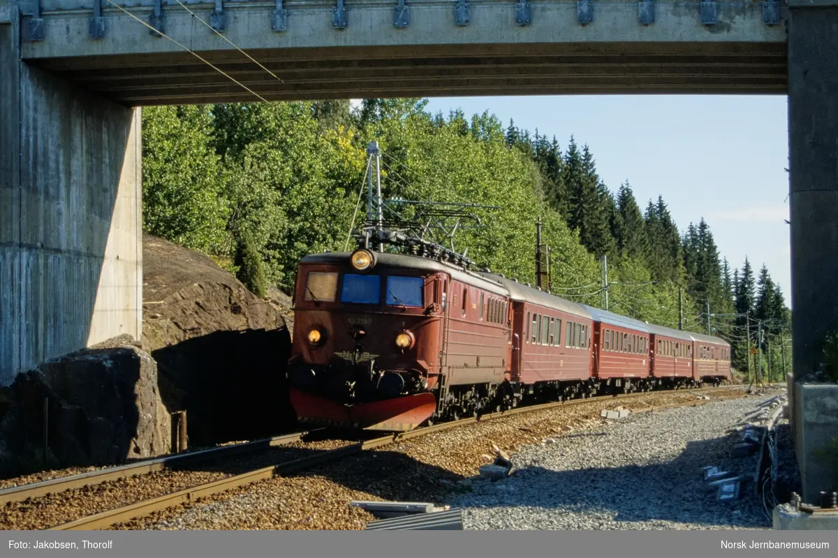 Elektrisk lokomotiv El 13 2158 med hurtigtog fra Halden til Oslo S, tog 152, ved Tveter mellom Ås og Vestby stasjoner på Østfoldbanen. Ny overgangsbru har erstattet planovergang