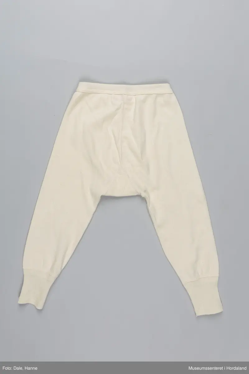 Underbukse med bråt i liv og på bein, gylf, hull ved hoftene, hull til snøring på innsiden av livbråt og korte bein.
Den er pakka i rektangulær plastemballasje med ileggspapp.