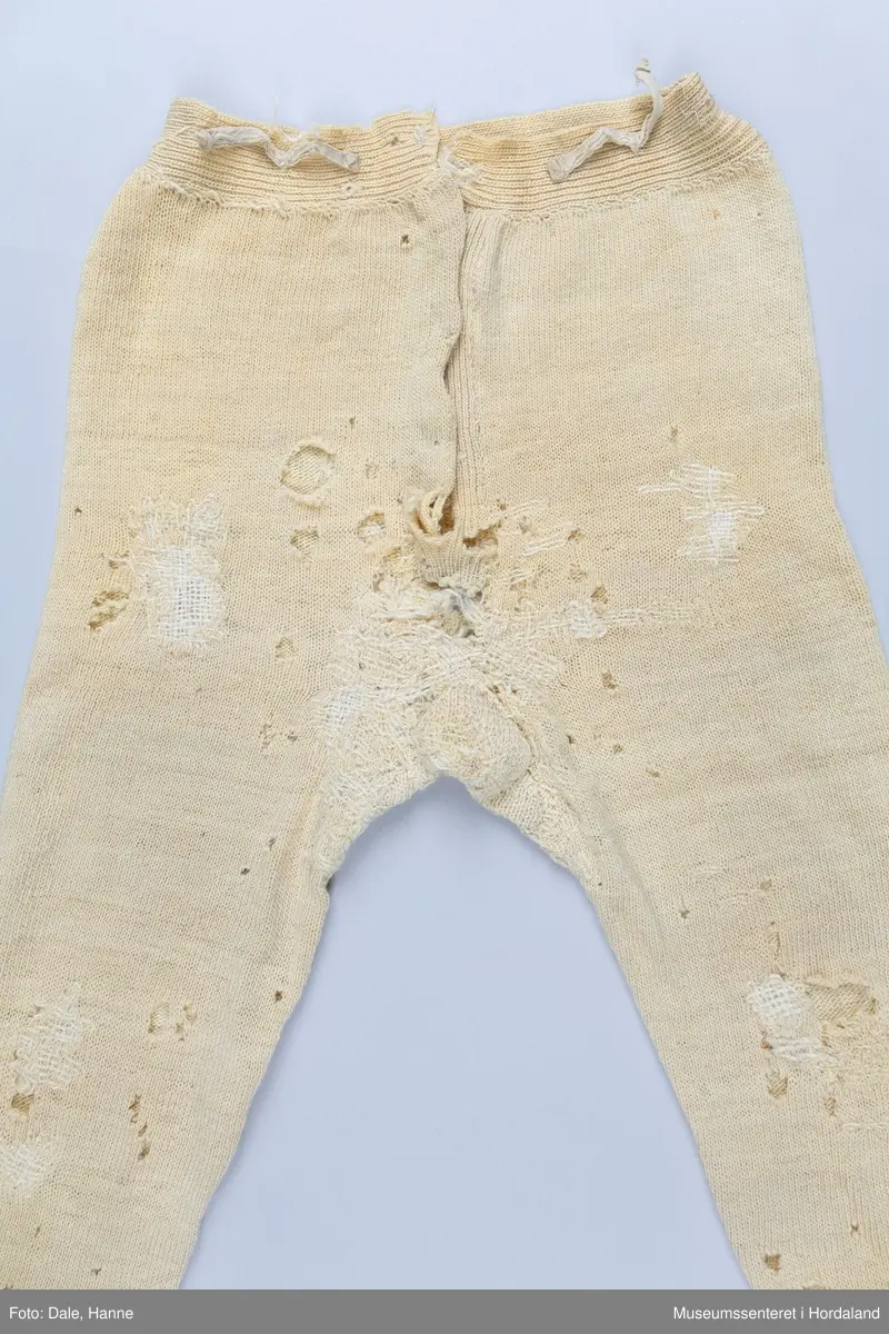 Strikka underbukse med bråt på bein og i livet, strikk og hemper i livet, og knappegylf. Buksa har mange hol, og er stoppa mange gongar, spesielt i skrittet i fronten av buksa.
