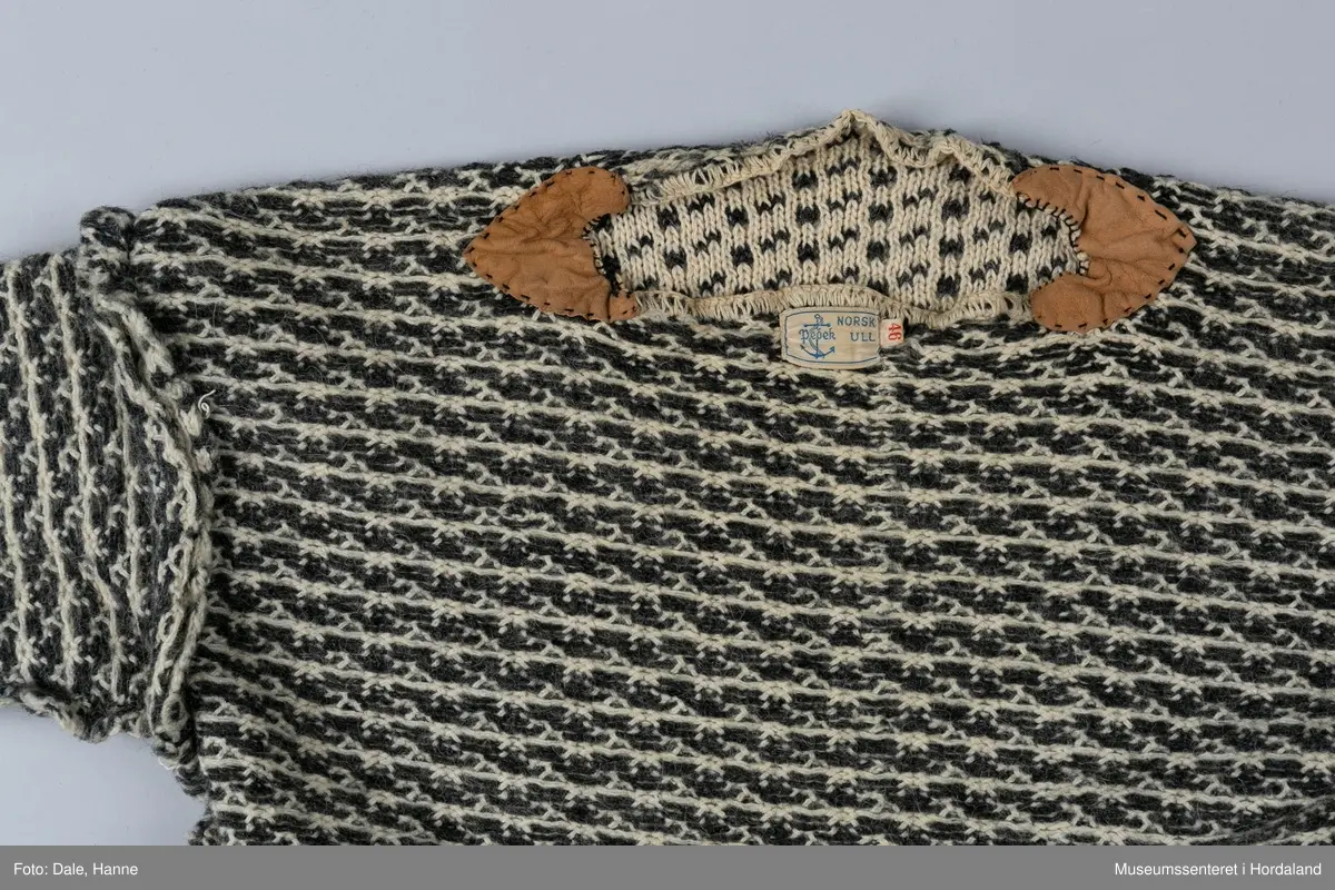 Strikka naturfarga ullgenser med koksgrått klassisk islendermønster. Merkelapp "Pedek - norsk ull" (str. 46) i halsopningen. Hals- og ermeopningane er hekla over med naturfarga garn som reparasjon, og det er festa skinnlappar på kvar side av halsen på innsida av genseren. Venstre albogen er stoppa. Etter lang bruk har genseren begynt å rakne litt i nedre kant, og nokre masker enkelte andre stadar.