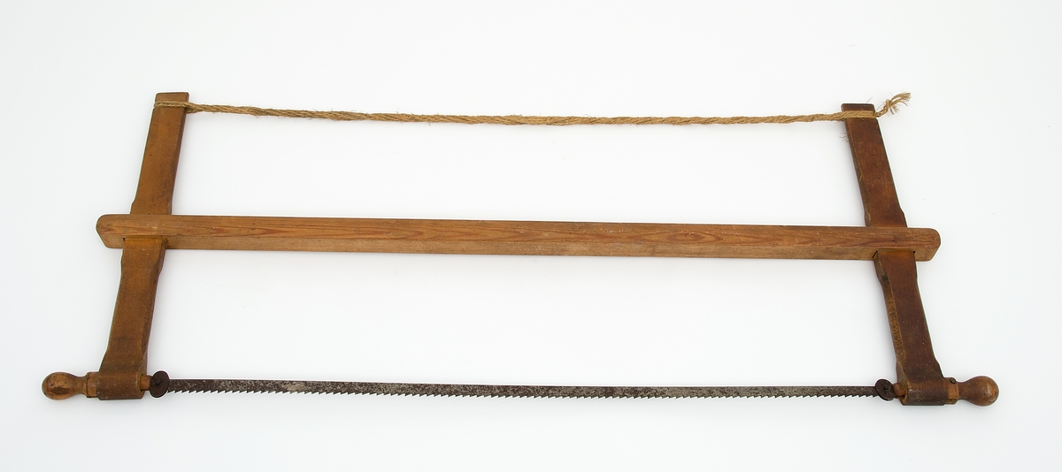 Grindsag med vendbart sagblad, bom og sagstrekk i tauverk med spennpinne. Tilvirket av ubehandlet treverk. Ved å vri sagbladet kan saga brukes til å kappe et bord på langs f.eks. - uten at grida kommer i veien.