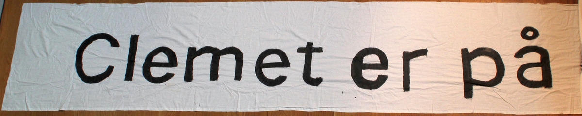 Banner frå arkivet til Norsk Målungdom. To bilete av eitt banner. På banneret står teksten: "Clemet er på sidespor". Det er truleg at banneret har vore i bruk under ein aksjon for Norsk Målungdom.