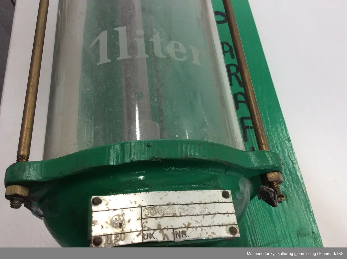 Pumpa består av en væskebeholder av glass med en volum av 5 liter. Under den er det en fordeler med en messingspak. Derifra går det to kobberledninger, en til en kort slange med munnstykke, den andre til en pumpemekanisme med en spak med treåndtak som fører til en tykkere slage med lang munnstykke. Den tredje slangen er tykkest og kuttet i enden. Under fordeleren er det en rund dryppe skål med avløpshull. Pumpa er montert på to treplanker som bakvegg som har tre lister som tverrforbinder. Øverst til høyre på bakveggen er det påført en fabrikkskilt av aluminium. Til høyre for glassbeholderen er det ordet PARAFIN vertikalt påskrevet.. 