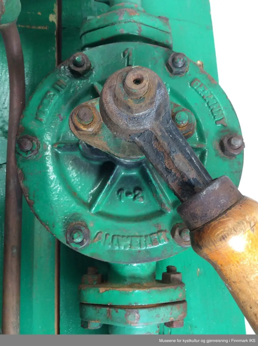 Pumpa består av en væskebeholder av glass med en volum av 5 liter. Under den er det en fordeler med en messingspak. Derifra går det to kobberledninger, en til en kort slange med munnstykke, den andre til en pumpemekanisme med en spak med treåndtak som fører til en tykkere slage med lang munnstykke. Den tredje slangen er tykkest og kuttet i enden. Under fordeleren er det en rund dryppe skål med avløpshull. Pumpa er montert på to treplanker som bakvegg som har tre lister som tverrforbinder. Øverst til høyre på bakveggen er det påført en fabrikkskilt av aluminium. Til høyre for glassbeholderen er det ordet PARAFIN vertikalt påskrevet.. 