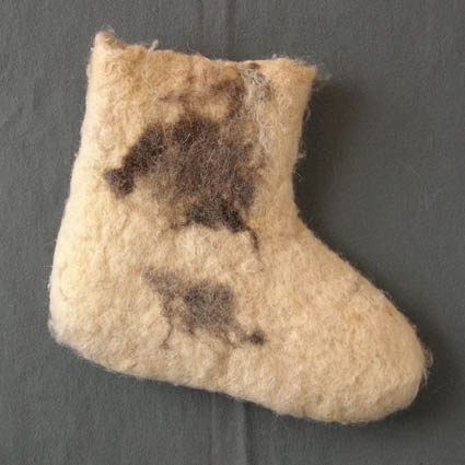 Socka tovad av naturvit ull, troligtvis ryaull, där locken fortfarande syns. Som dekoration är en fläck av naturgrå och natursvart ull intovad både på in- och utsidan av skaftet. Sockan är inte tovad så väldigt hårt och skaftets kant är naturligt avslutad och ojämn.