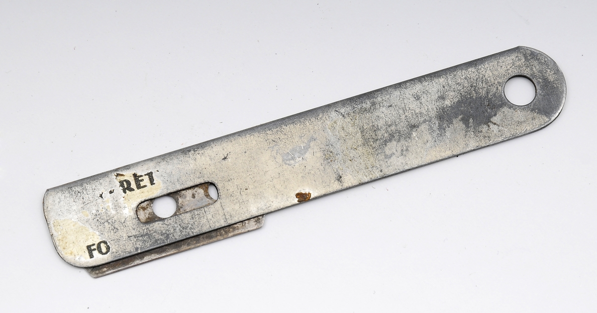 To mulige tapetkniver eller skjæreverktøy. Kniven består av et tynt, linjalformet metallstykke med rom for å føre inn et barberblad i den ene enden. I den andre enden er det et hull, muligsens til å henge opp kniven etter.