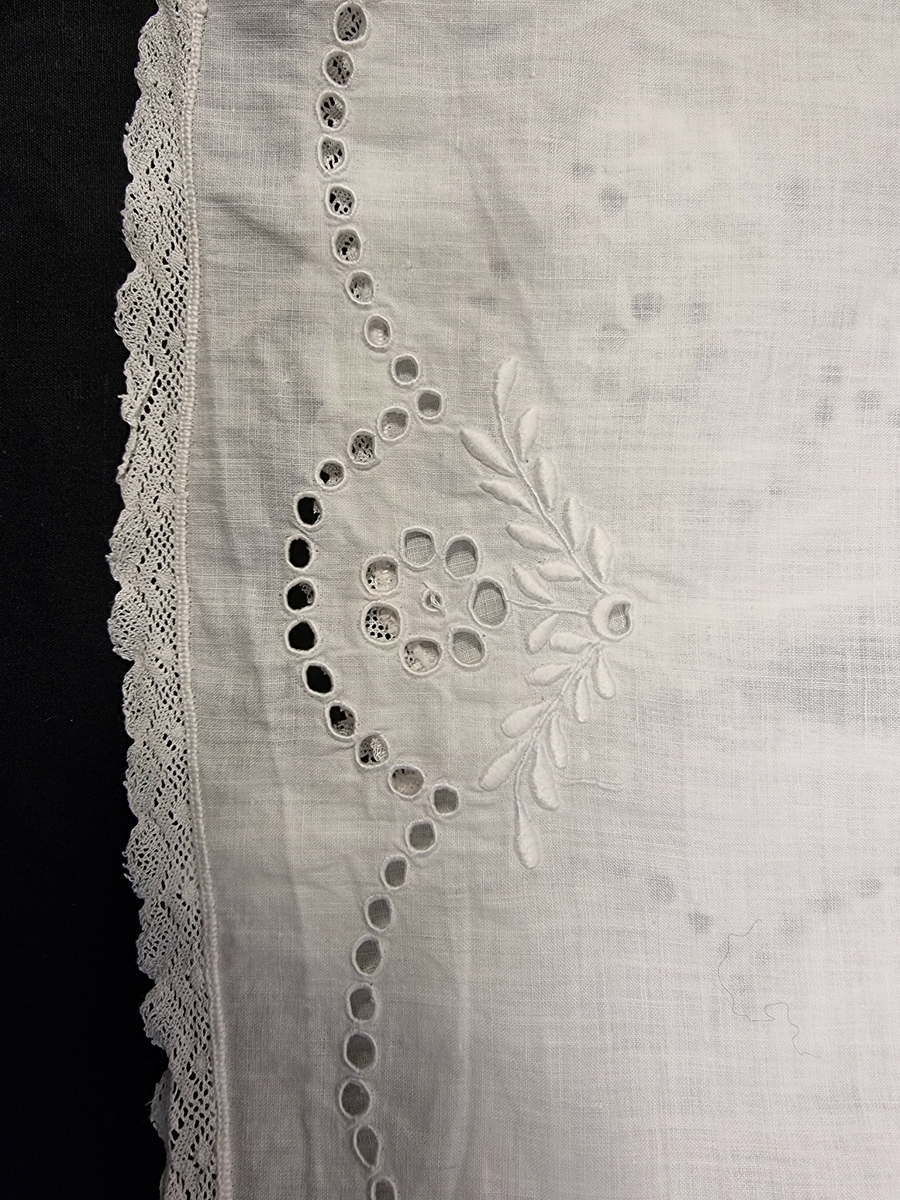 Skjorte med krage og lange armer, åpen i rygg. Småblonder på ermer og langs hele kanten. Brodert med engelsk broderi på krage og rundt på hele skjorten.