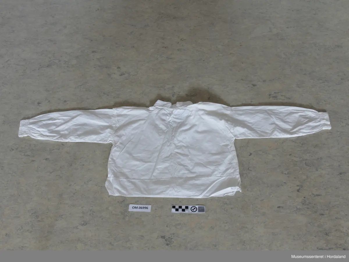 kvitsaum i halslinning, blondekant i bringa.