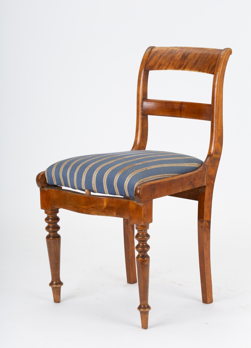 Stol, Biedermeier. Stoppet løst sete, gråblått ullstoff med grå og hvite smale striper. Dreide forben. Svai i rygg og bakben. 2 ryggspiler.
Kaffeflekker på stoltrekkene