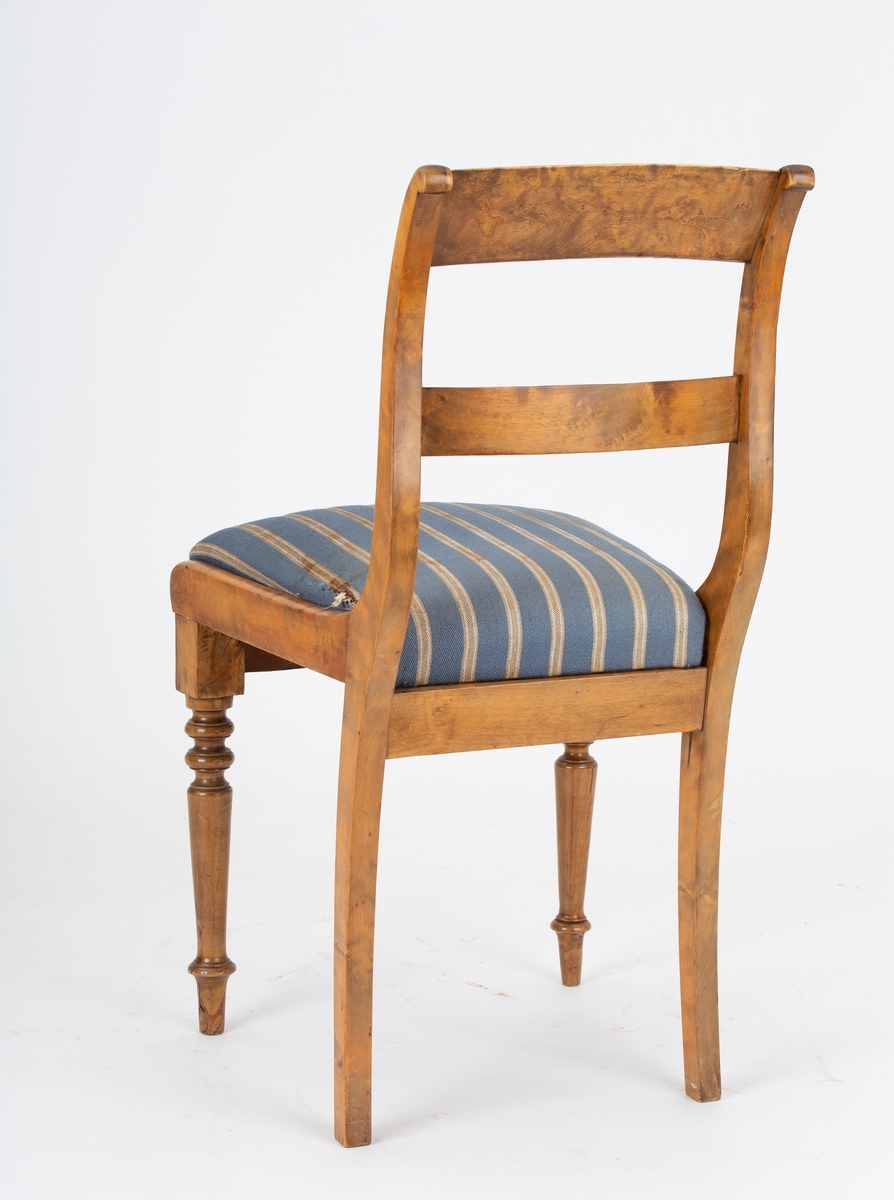 Stol, Biedermeier. Stoppet løst sete, gråblått ullstoff med grå og hvite smale striper. Dreide forben. Svai i rygg og bakben. 2 ryggspiler.
Kaffeflekker på stoltrekkene