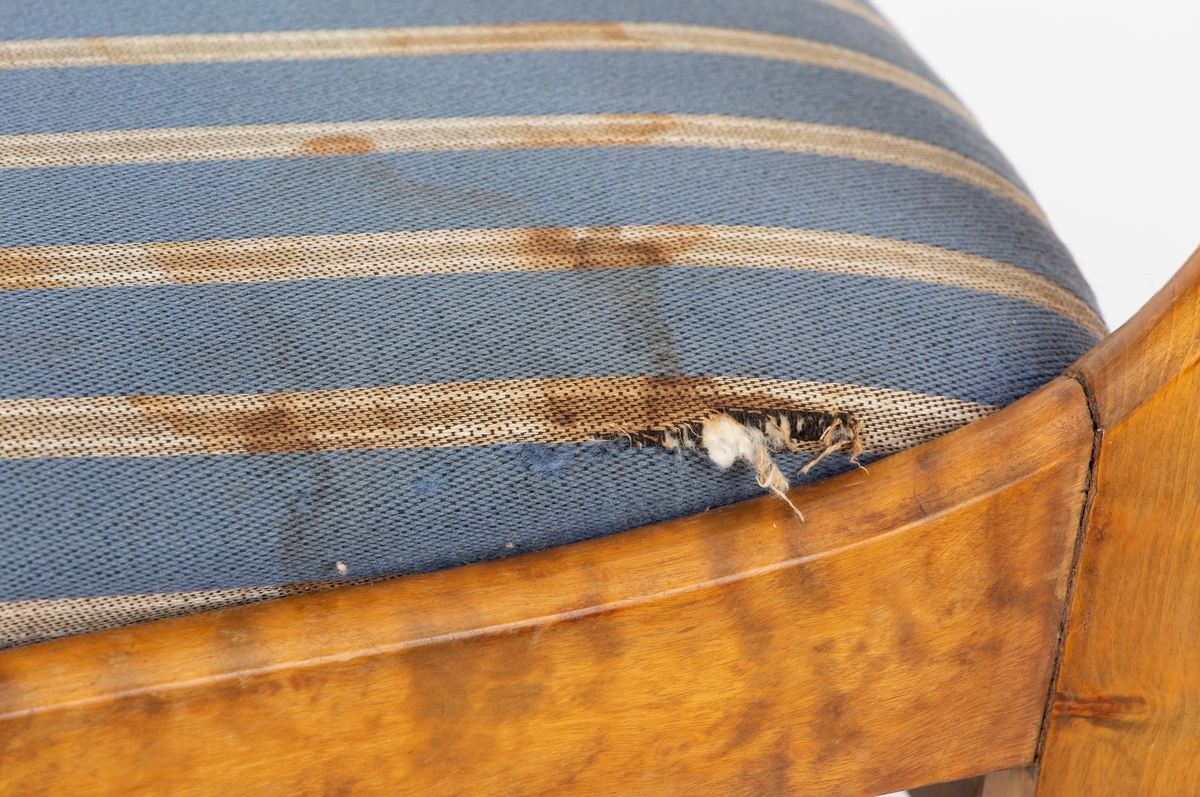 Stol, Biedermeier. Stoppet løst sete, gråblått ullstoff med grå og hvite smale striper. Dreide forben. Svai i rygg og bakben. 2 ryggspiler.
Kaffeflekker på stoltrekkene