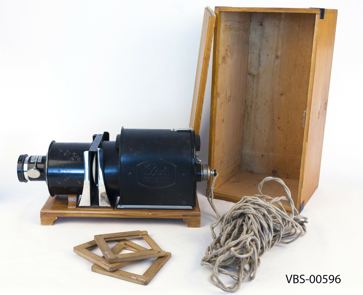 Lysbildefremviser apparat med 80 mm objektiv, 3 treskinne for bilder og trekasse. 
Gjenstanden er montert på en lakkert eikeplattform, med små ben og bue for å støtte sylinderen med de indre forstørrelseslinsene. Fast montert ujordet strømkabel og intakt indre lyspære.  Manuell framføring av lysbilder ved hjelp av treskinne beregnet for 35 mm lysbilder i ramme.