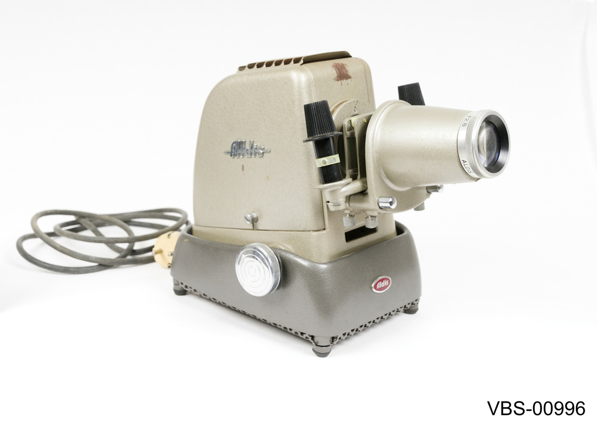 Fremviser Aldis, modell Star 300, i metall lakkert med sølvgrå farge. Objektiv med 10 cm linse og F 2.8.
Koffert i bronsefarge kartong (tekstil tekstur) med beige og hvitt stripete papirtrekk på innsiden. Håndtak i svart bakelitt og beslag i sølvfarget metall. Den har en liten intern papp skuff med trykklås som inneholder instruksjonspapirene av fremviser.