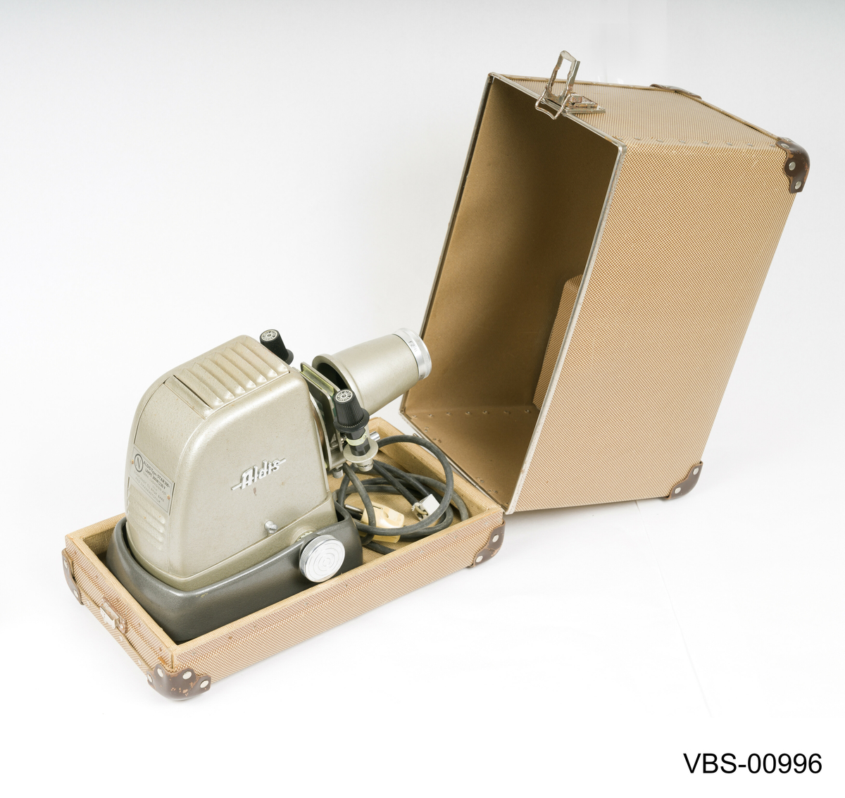 Fremviser Aldis, modell Star 300, i metall lakkert med sølvgrå farge. Objektiv med 10 cm linse og F 2.8.
Koffert i bronsefarge kartong (tekstil tekstur) med beige og hvitt stripete papirtrekk på innsiden. Håndtak i svart bakelitt og beslag i sølvfarget metall. Den har en liten intern papp skuff med trykklås som inneholder instruksjonspapirene av fremviser.