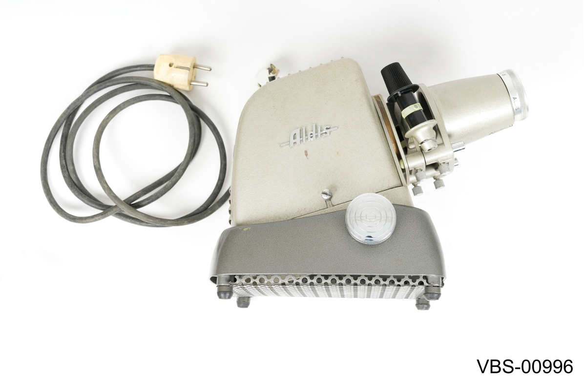 Fremviser Aldis, modell Star 300, i metall lakkert med sølvgrå farge. Objektiv med 10 cm linse og F 2.8.
Koffert i bronsefarge kartong (tekstil tekstur) med beige og hvitt stripete papirtrekk på innsiden. Håndtak i svart bakelitt og beslag i sølvfarget metall. Den har en liten intern papp skuff med trykklås som inneholder instruksjonspapirene av fremviser.